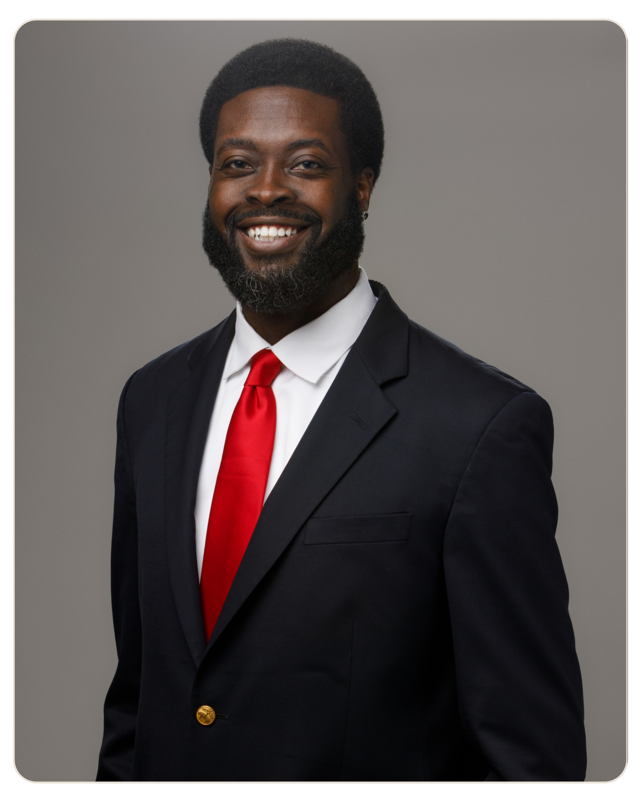 Ahmad Bryant Chief Executive Officer Smiling man in a dark suit and red tie against a gray backdrop