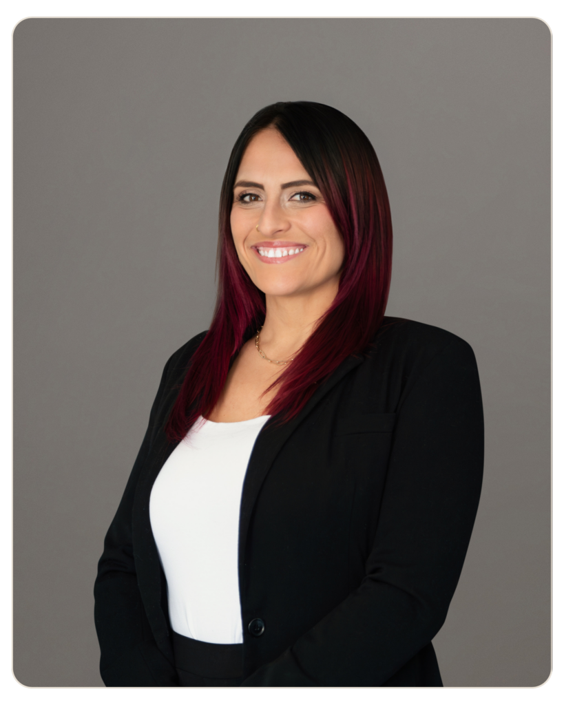 Professional head-and-shoulders portrait of a smiling woman in a black blazer against a gray backdrop.