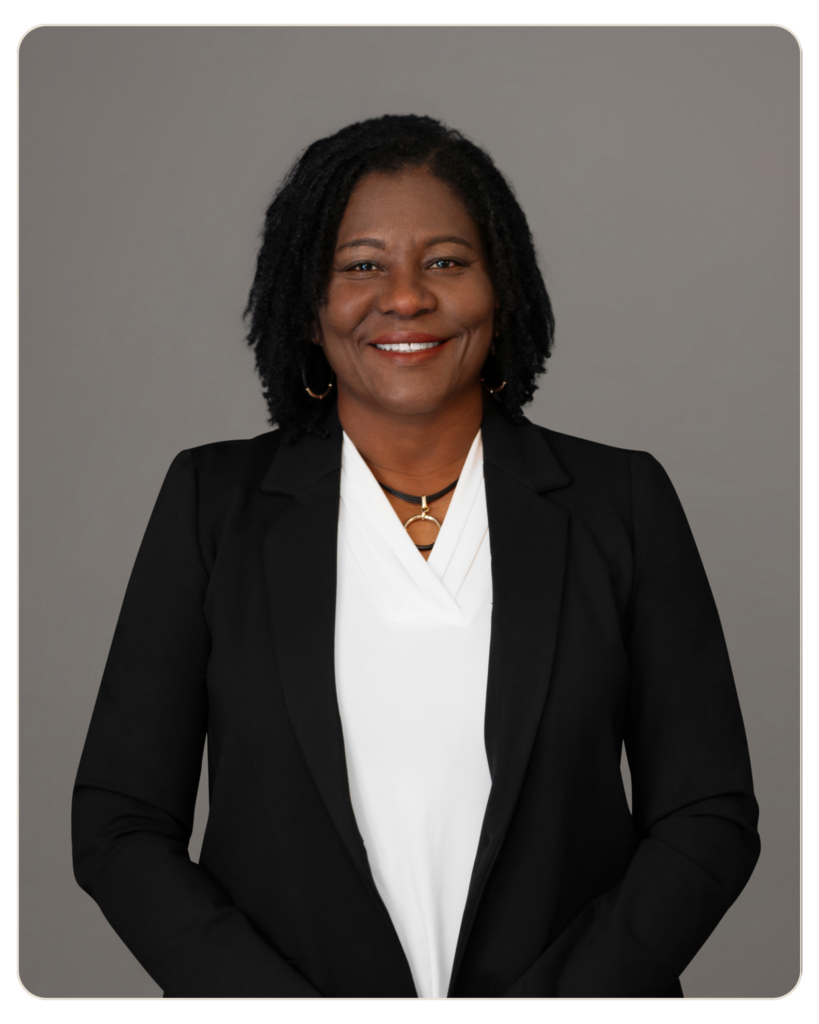 Marie Eliacin, RN BSN Director of Nursing Professional headshot of an African American woman in a black blazer and white blouse, smiling warmly against a neutral gray background.