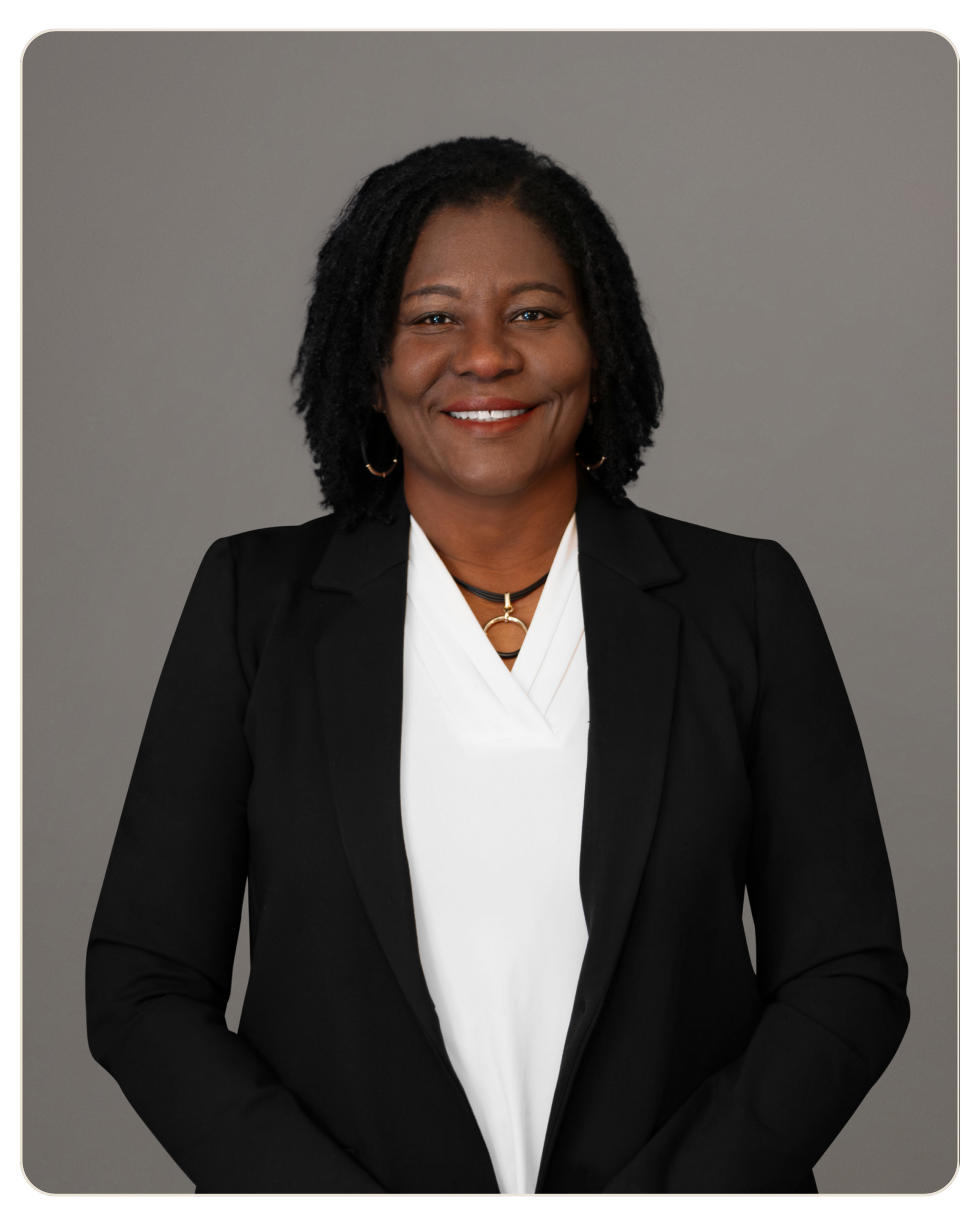 Marie Eliacin, RN BSN Director of Nursing Professional headshot of an African American woman in a black blazer and white blouse, smiling warmly against a neutral gray background.